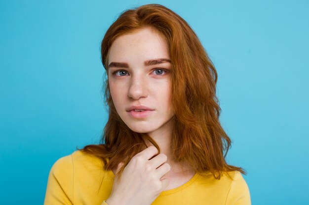 Headshot Portrait d&#39;une fille heureuse de gingembre avec des taches de rous souriantes en regardant la caméra. Fond bleu pastel. Espace de copie.