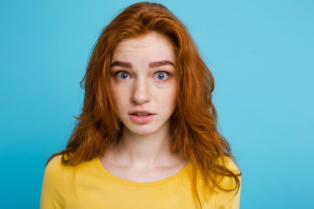 Headshot Portrait d&#39;une fille heureuse de gingembre avec des taches de rous souriantes en regardant la caméra. Fond bleu pastel. Espace de copie.