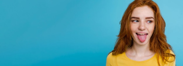 Photo gratuite headshot portrait of happy ginger red hair girl with funny face looking at camera pastel blue backgr