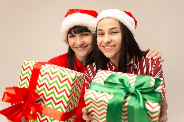 Héhé en pull de Noël posant avec des cadeaux. Profiter des câlins d'amour, des gens de vacances. Maman et doughter sur fond gris dans le studio