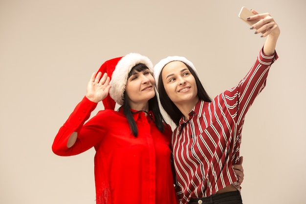 Héhé en pull de Noël posant avec des téléphones mobiles