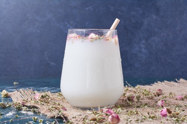 Herbes avec une tasse de boisson sur bleu.