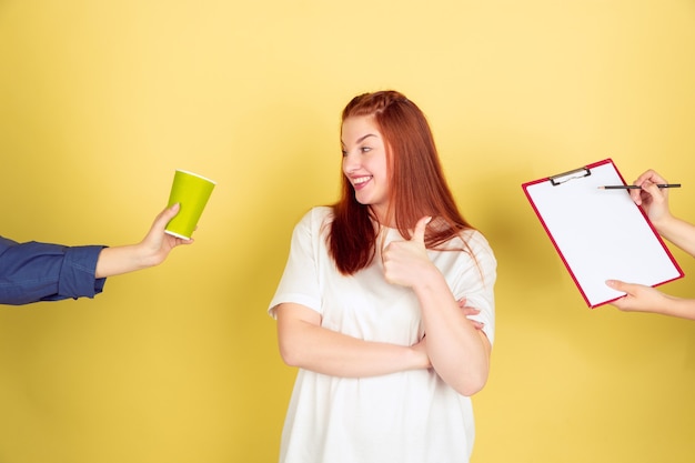 L'heure du café. Portrait de jeune femme caucasienne sur fond de studio jaune, trop de tâches. Comment bien gérer son temps. Concept de travail de bureau, entreprise, finance, pigiste, autogestion, planification.