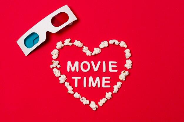 Heure du film écrit en forme de coeur avec des lunettes 3d sur fond rouge