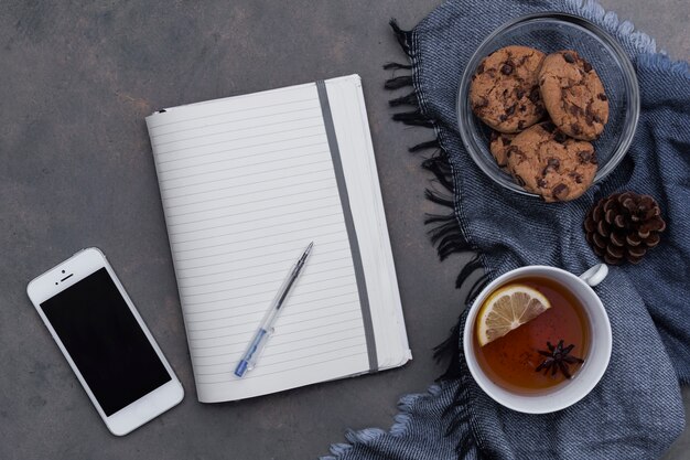 L&#39;heure du thé avec des biscuits sur le plaid bleu avec le bloc-notes