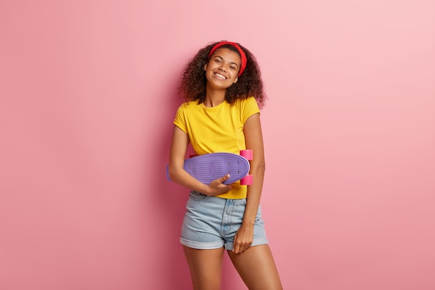 Heureuse adolescente aux cheveux bouclés posant en tshirt jaune