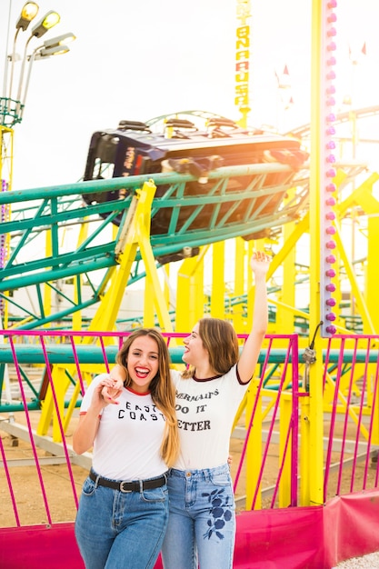 Photo gratuite heureuse amies traîner ensemble devant le roller coaster