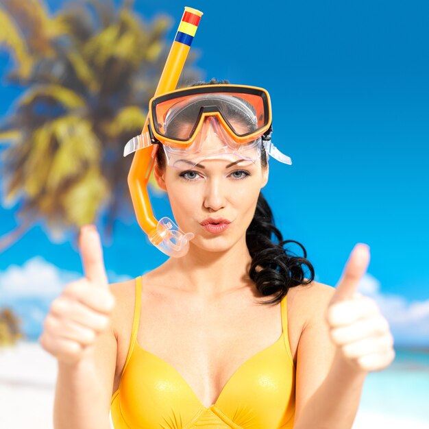 Heureuse belle femme sur la plage avec signe de pouce en l'air.