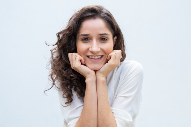 Heureuse belle femme se penchant le menton et la tête sur les mains