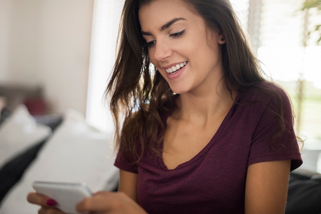 Heureuse belle jeune femme avec smartphone à la maison