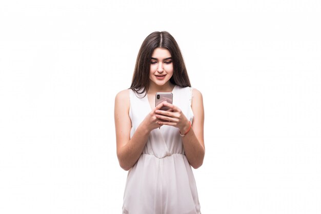 Heureuse belle jeune mannequin en robe blanche moderne sur blanc avec téléphone