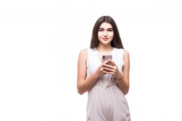 Heureuse belle jeune mannequin en robe blanche moderne sur blanc avec téléphone