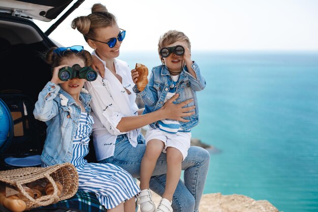 heureuse belle mère et ses enfants voyagent en voiture près de la mer