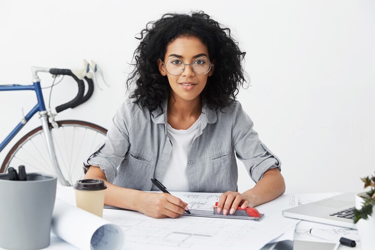 Photo gratuit heureuse belle métisse ingénieur femme faisant des dessins ou des croquis à l'aide d'une règle