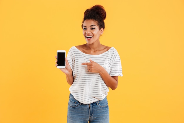 Heureuse dame africaine montrant le téléphone avec écran blanc isolé