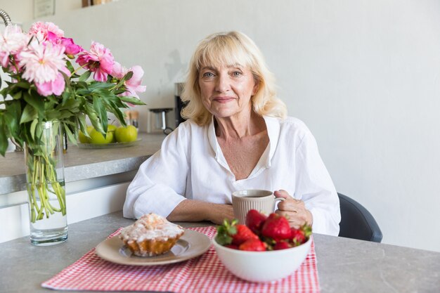 Heureuse dame mature assise avec une tasse de café