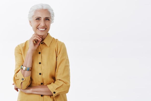 Heureuse dame senior à la mode en manteau jaune souriant joyeux