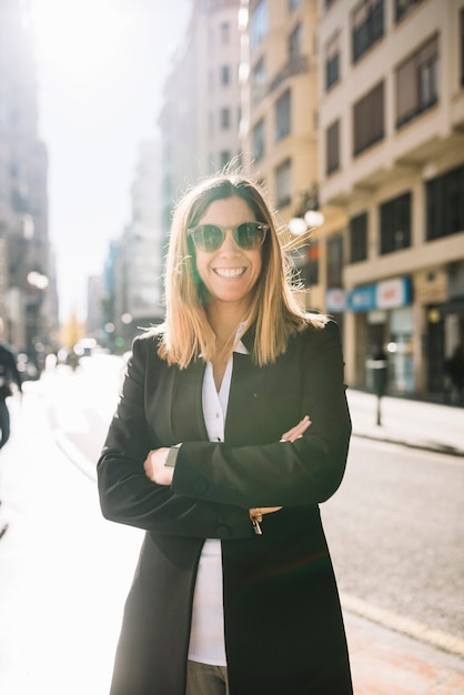 Heureuse élégante jeune femme avec des lunettes de soleil sur la rue en journée ensoleillée