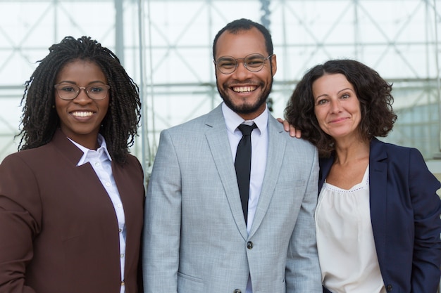 Photo gratuite heureuse équipe professionnelle unie posant dans le couloir