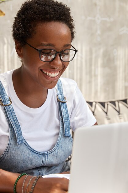 Heureuse étudiante noire se prépare à l'examen universitaire, travaille dans un café