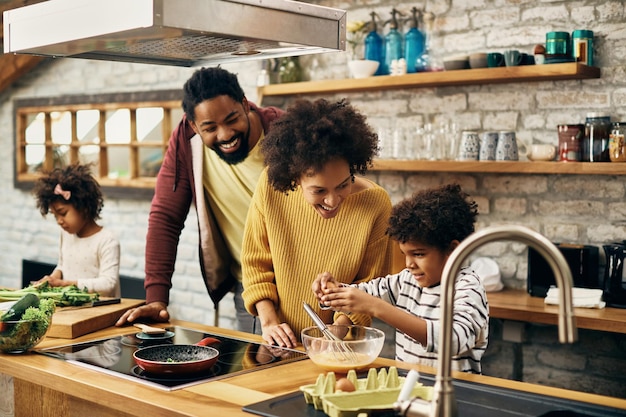 Photo gratuite heureuse famille afro-américaine appréciant tout en préparant le repas ensemble dans la cuisine