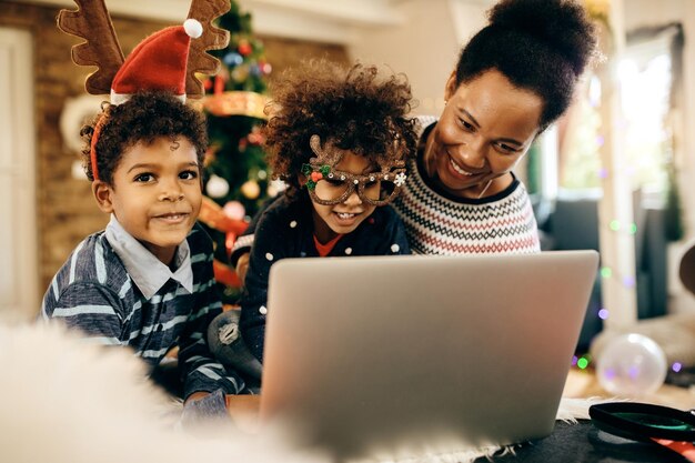 Heureuse famille afro-américaine surfant sur le net sur un ordinateur portable à Noël à la maison