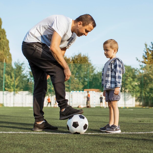 Heureuse famille monoparentale apprenant à jouer au football