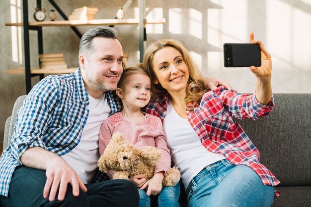 Heureuse famille prenant selfie sur un canapé
