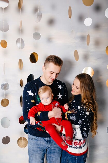 Heureuse famille souriante au studio sur fond de l&#39;arbre de Noël avec cadeau