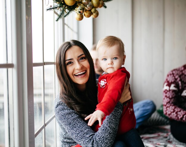 Heureuse famille souriante au studio sur fond de l&#39;arbre de Noël avec cadeau