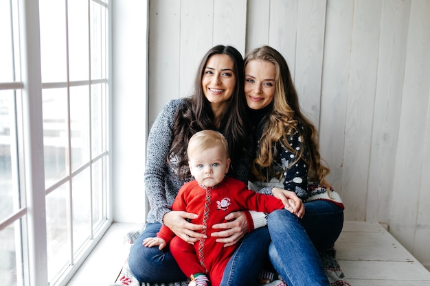 Heureuse famille souriante au studio sur fond de l&#39;arbre de Noël avec cadeau