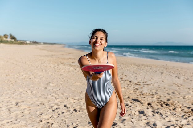 Heureuse femme adulte pointant à la caméra avec une raquette de tennis