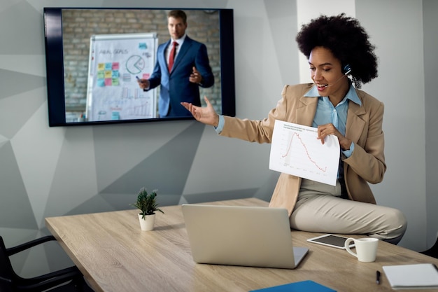 Photo gratuite heureuse femme d'affaires afro-américaine analysant le diagramme lors d'une réunion en ligne au bureau