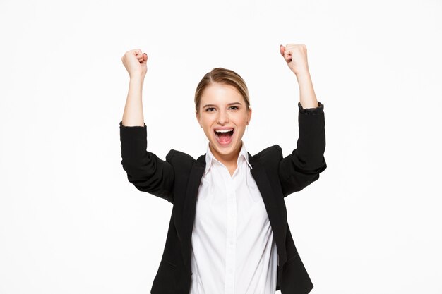 Heureuse femme d'affaires blonde qui crie sur mur blanc