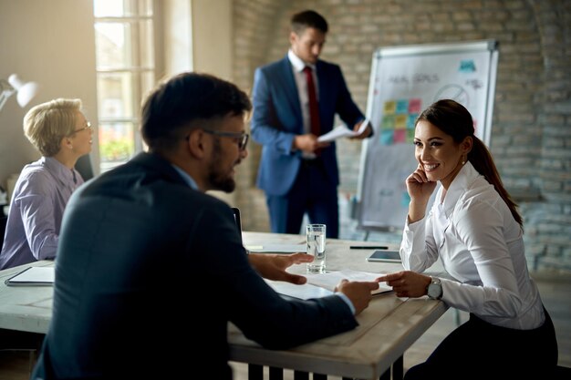 Heureuse femme d'affaires communiquant avec son collègue lors d'une réunion au bureau