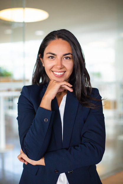 Heureuse femme d'affaires avec la main sur le menton