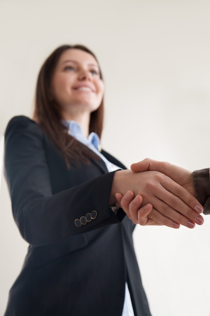 Heureuse femme d&#39;affaires portant costume serrant la main masculine, se concentrer sur la poignée de main