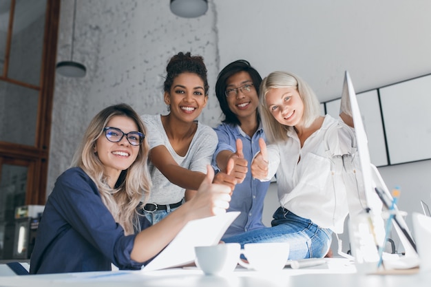 Heureuse femme africaine chef du département marketing posant avec le pouce vers le haut après un travail acharné