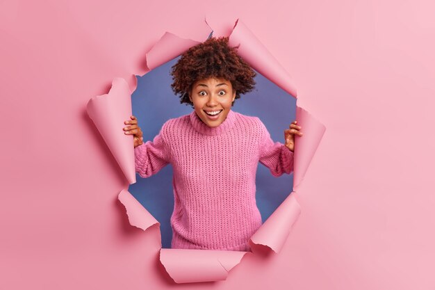 Heureuse femme afro-américaine surprise regarde la caméra et voit quelque chose d'étonnant