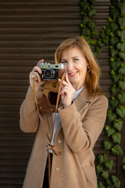 Heureuse femme d'âge moyen tenant un appareil photo