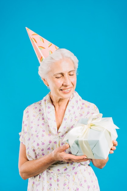 Photo gratuite heureuse femme âgée avec cadeau d'anniversaire sur fond bleu