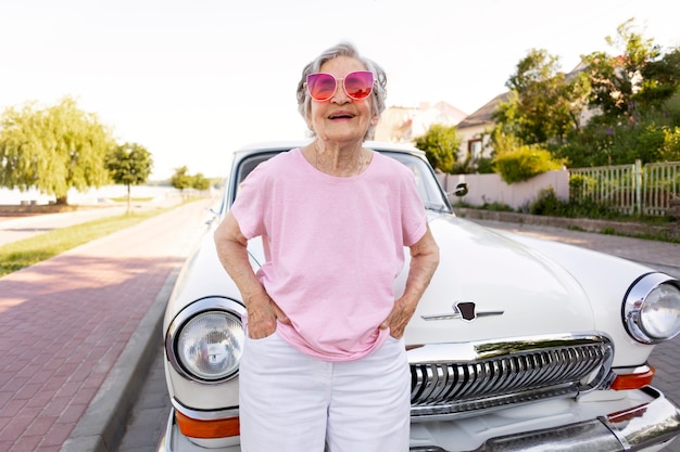 Heureuse femme âgée debout à côté de sa voiture