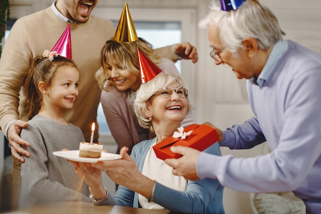 Heureuse femme âgée s'amusant tout en célébrant son anniversaire avec sa famille à la maison