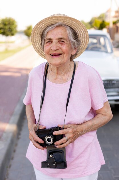 Heureuse femme âgée tenant un appareil photo en voyage