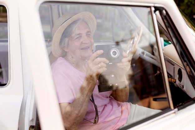 Heureuse femme âgée tenant un appareil photo en voyage