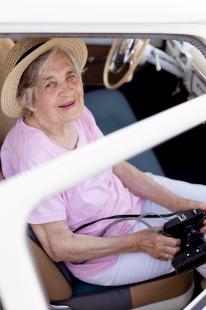 Heureuse femme âgée tenant un appareil photo en voyage