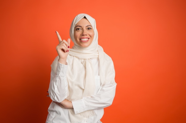 Heureuse femme arabe en hijab. Portrait de jeune fille souriante, posant au fond de studio rouge.