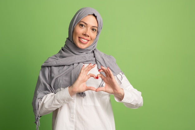 Photo gratuite heureuse femme arabe en hijab. portrait de jeune fille souriante, posant au studio vert.