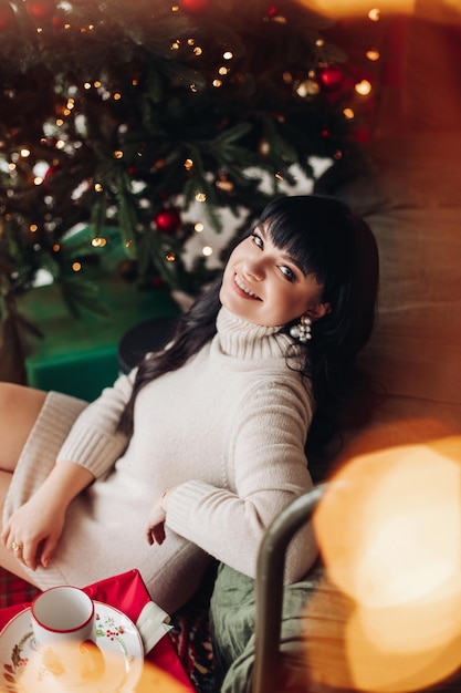 Heureuse femme à un arbre de Noël tournant son visage souriant vers la caméra