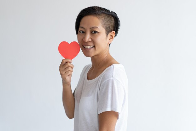 Heureuse femme asiatique tenant coeur de papier